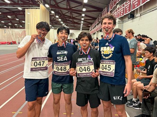 Four brothers wearing race bibs and medals at a track meet