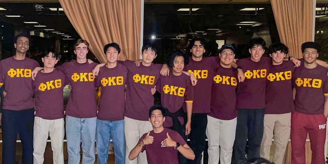 Brothers wearing matching Phi Kappa Theta shirts in the house
