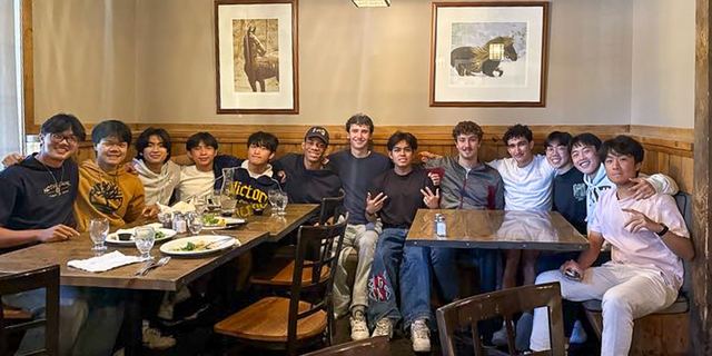 Brothers seated together around a long dinner table