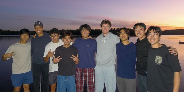 Brothers posing together by a lake at sunset
