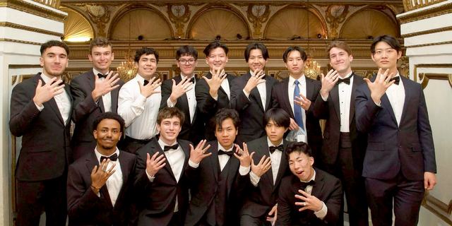 A large group of brothers dressed formally in an ornate hall
